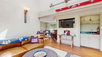 A modern living room with a leather sofa, a coffee table, and a TV mounted on the wall.