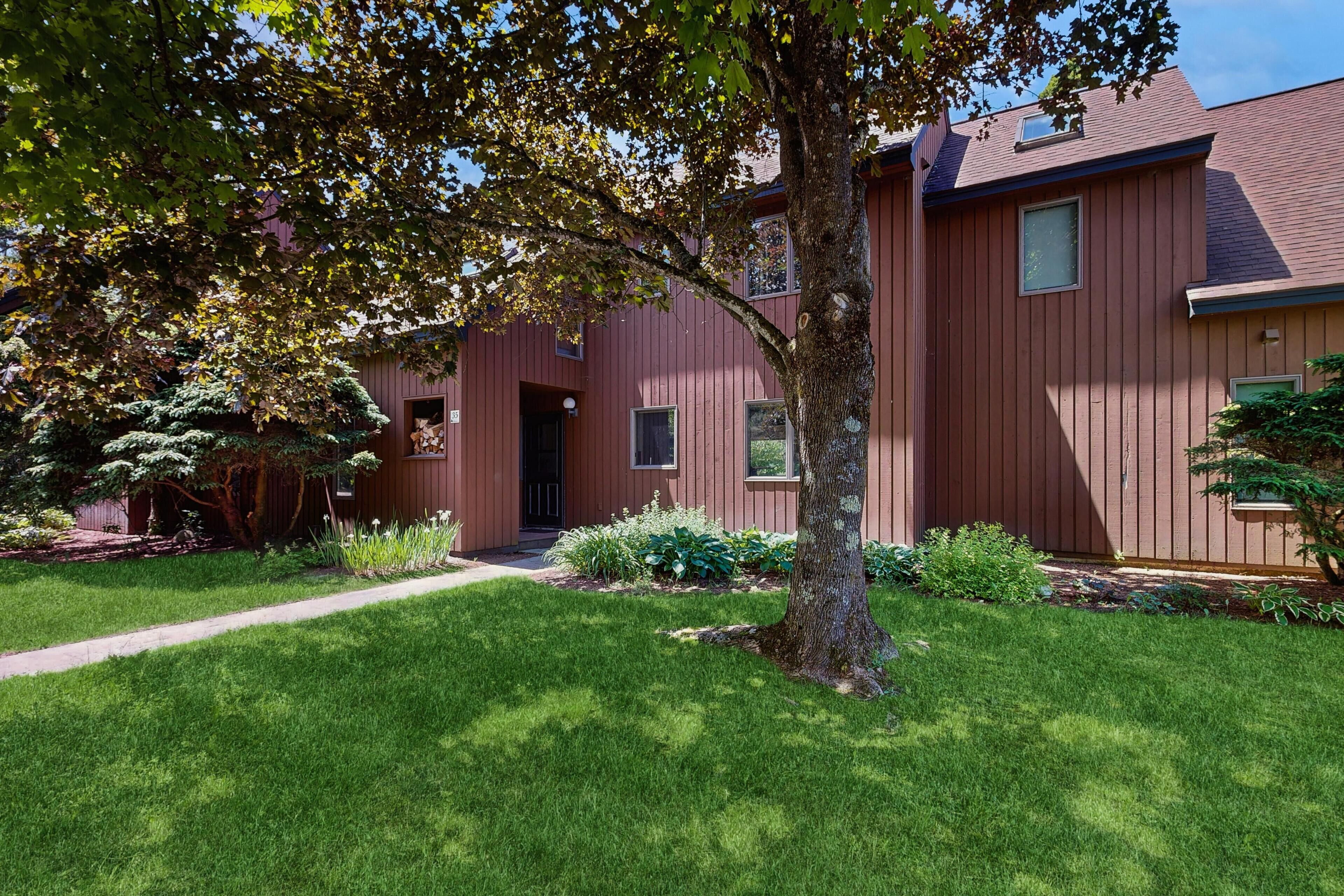 A red building with a well-maintained lawn and a tree in the foreground.