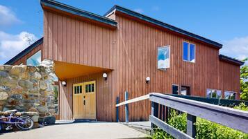 A wooden building with a stone wall entrance, a wooden door, and a ramp leading to the entrance.