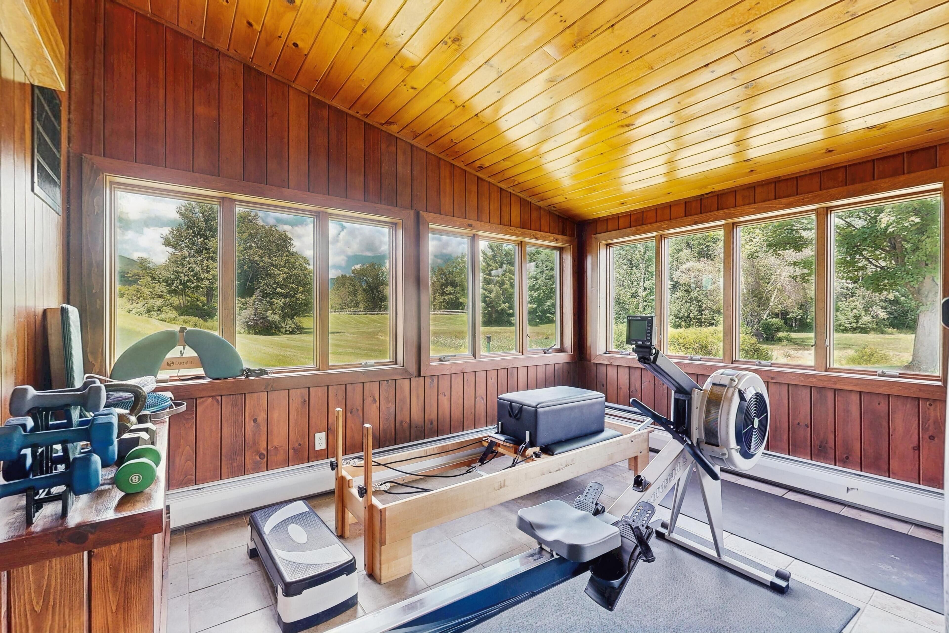 A gym with exercise equipment, large windows, and a view of the outdoors.