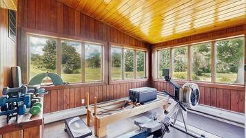 A gym with exercise equipment, large windows, and a view of the outdoors.