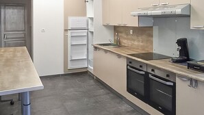 Een kleine keuken met een aanrecht, oven en koffiezetapparaat.