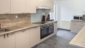 Een keuken met een kookplaat, oven, magnetron en een spoelbak.