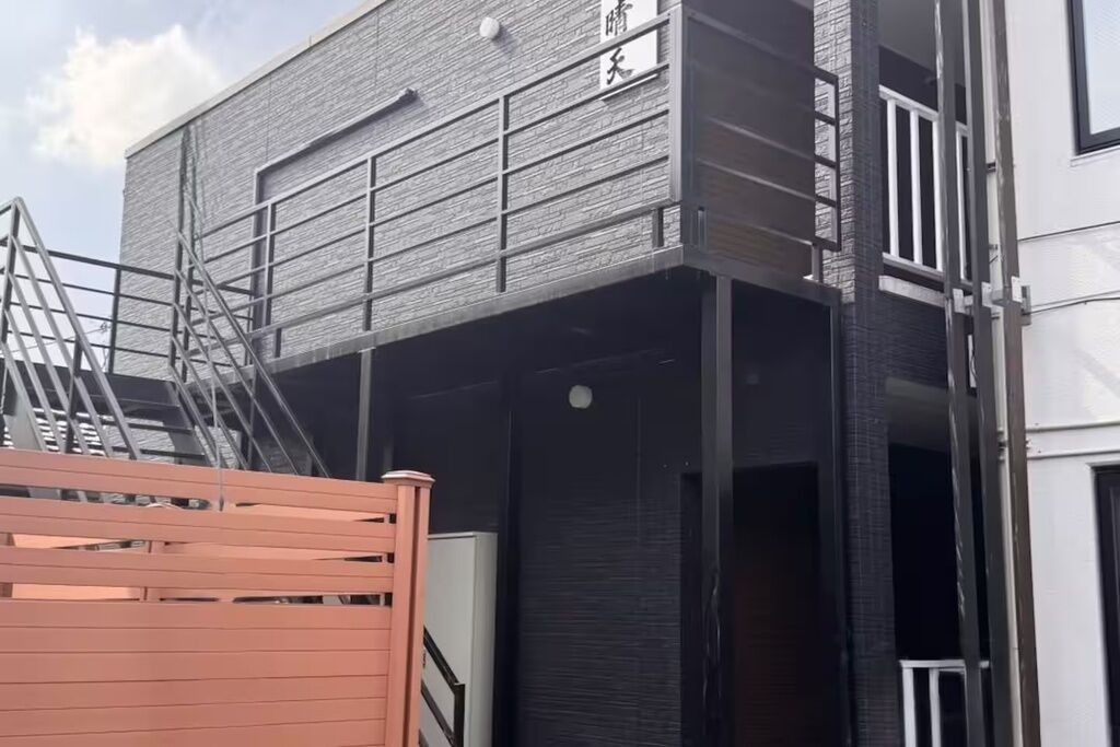 Um edifício com vários andares e design arquitetônico moderno, destacando uma escadaria e um portão de metal.