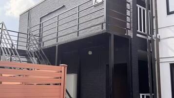 Um edifício com vários andares e design arquitetônico moderno, destacando uma escadaria e um portão de metal.