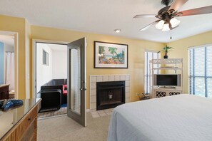 A hotel room with a bed, a fireplace, a television, and a ceiling fan. - Tops'l Tranquility | Townhome & the Gulf (Miramar Beach)