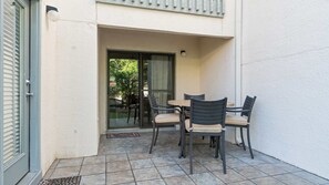 A patio area with a table and chairs, a sliding glass door, and a small rug. - Tops'l Tranquility | Townhome & the Gulf (Miramar Beach)