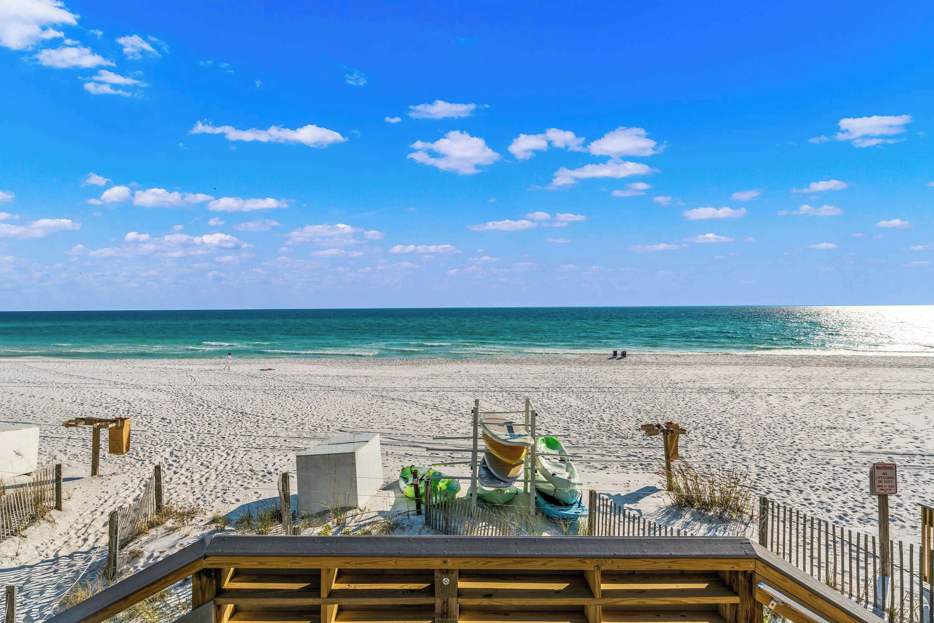 A beach with a wooden walkway leading to a lifeguard station.