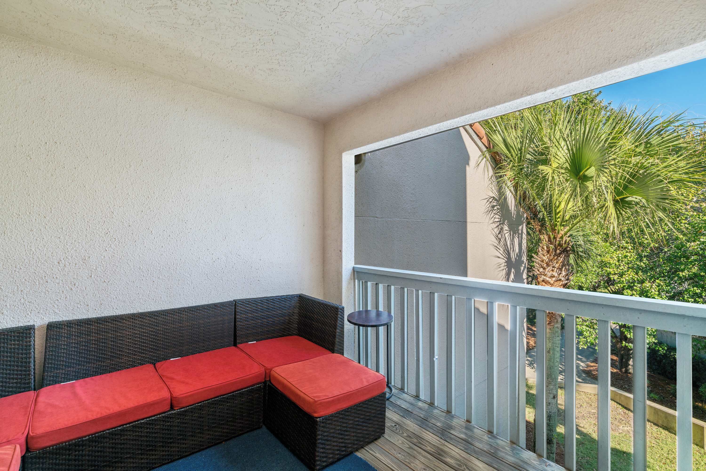 A balcony with a wicker sofa and a small table.