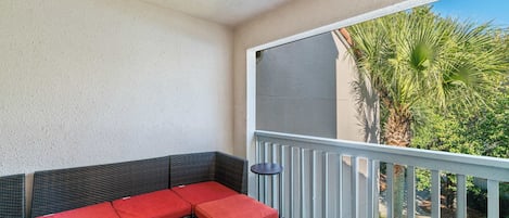 A balcony with a wicker sofa and a small table.