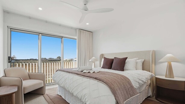 A modern hotel room with a large bed, a chair, a bedside table, and a view of the outside. - Woodlands Escape - 3 Bed, 2.5 Bath, Near Winery (Orange)