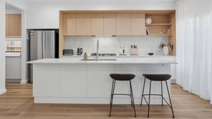 A modern kitchen with a central island, wooden cabinets, and a stainless steel refrigerator. - Woodlands Escape - 3 Bed, 2.5 Bath, Near Winery (Orange)
