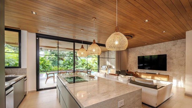 Una cucina moderna con una grande isola, un'area pranzo e una TV fissata alla parete.
