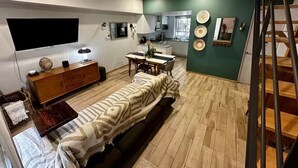 A modern living room with a sofa, a wooden cabinet, a dining table, and a kitchen area in the background. - Modern Townhouse in the Heart of Mixcoac! (Ciudad de México)