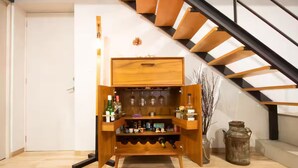 A wooden wine rack with bottles and a small cabinet, a staircase, and a rustic vase. - Modern Townhouse in the Heart of Mixcoac! (Ciudad de México)