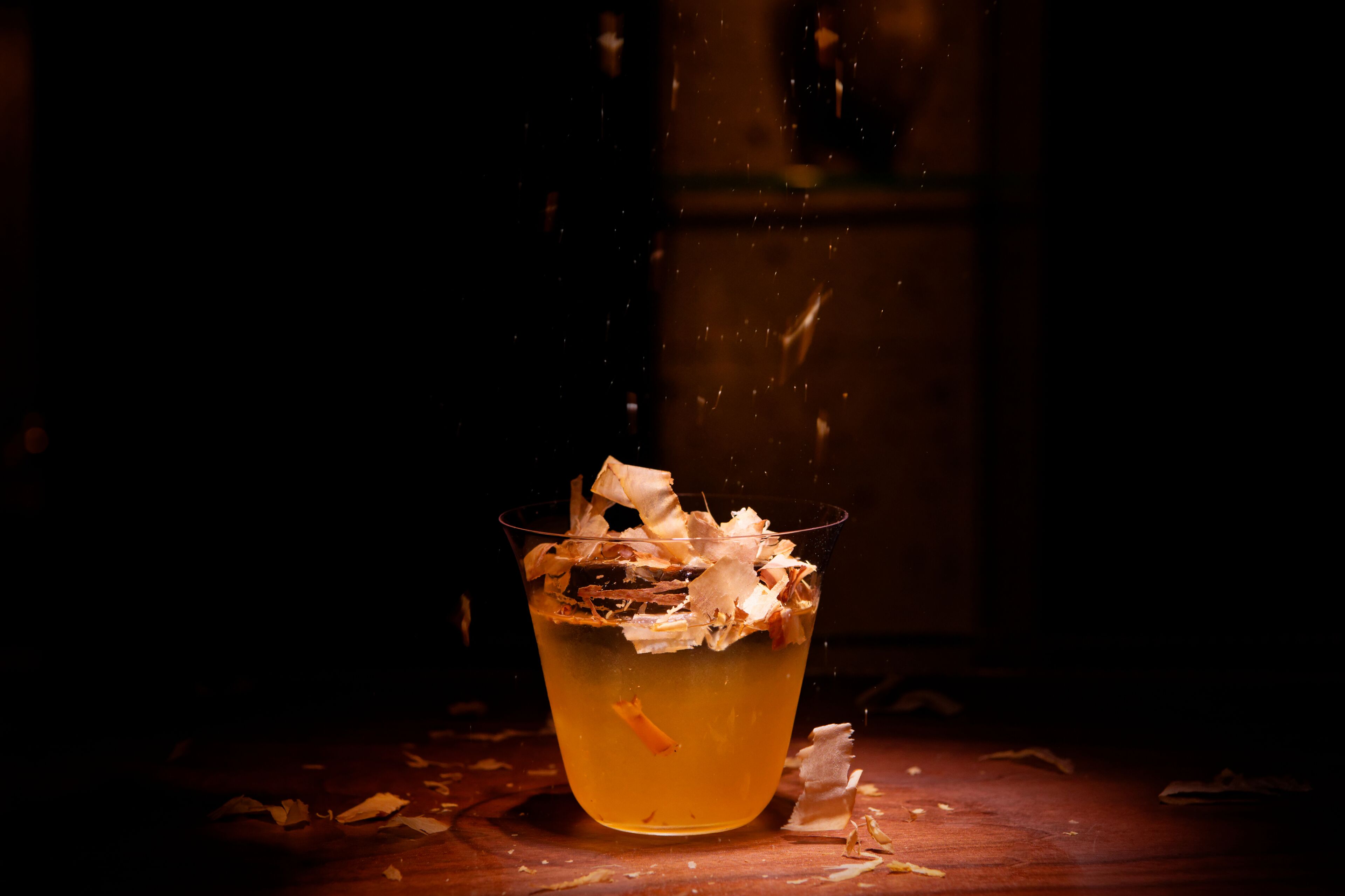 Un vaso con una bebida y un papel encima, sobre una superficie de madera.