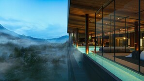 Un hôtel moderne doté d’une piscine à débordement en verre offrant une vue imprenable sur un paysage montagneux.