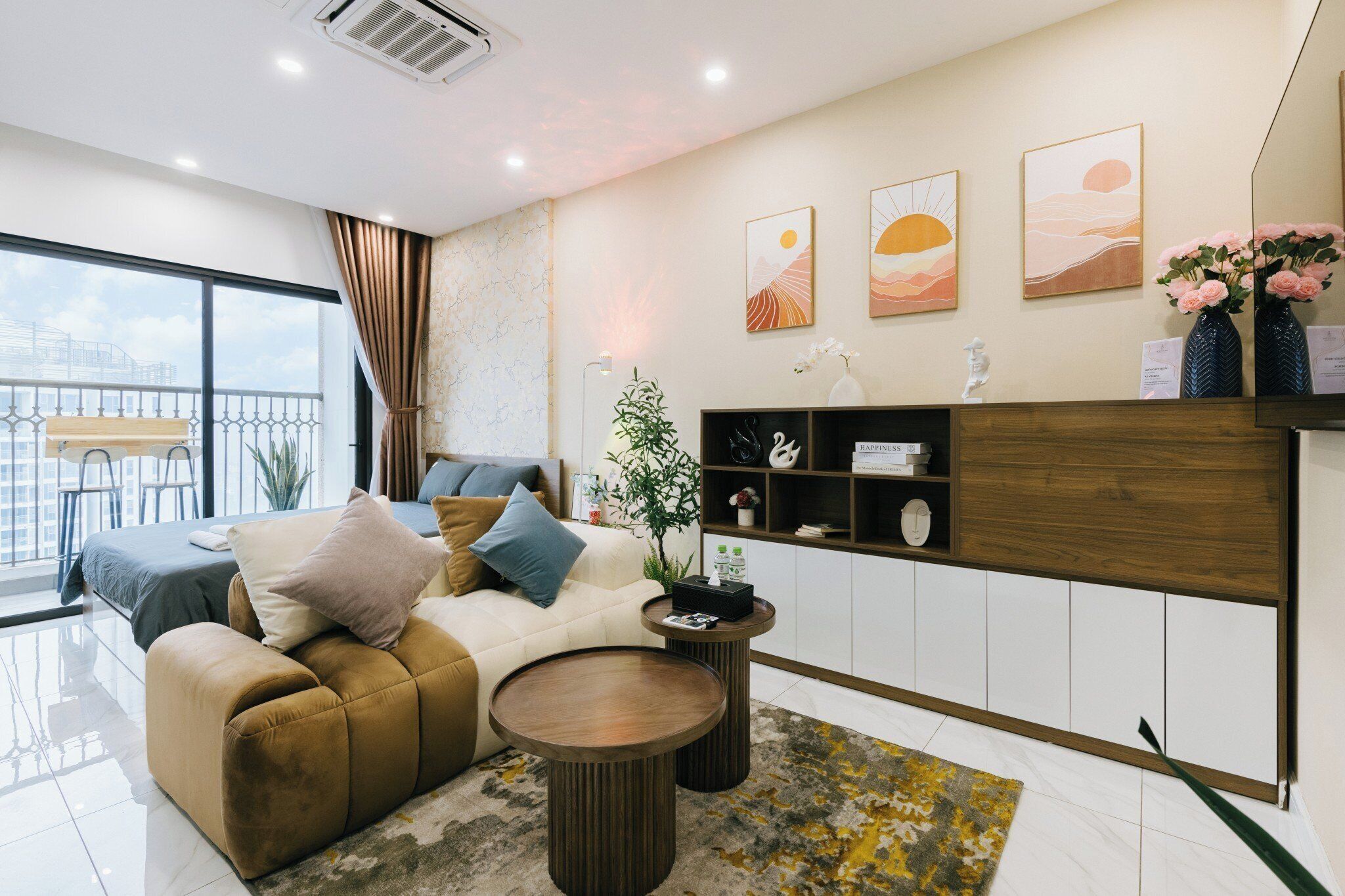 Een moderne woonkamer met een bank, salontafel en decoratieve objecten. Er is een balkon met een balustrade en uitzicht op de stad.