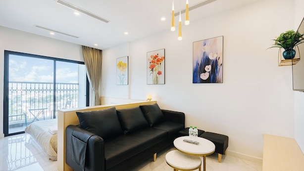 A modern living room with a black sofa, a small round table, and artwork on the walls. - D'. El Dorado Ho Tay Luxury Apartment  (Hanoi)