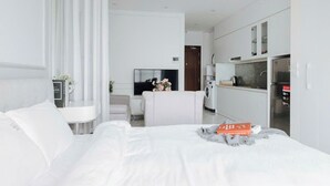 A modern hotel room with a bed, a TV, a sofa, a dining area, and a kitchen. - D'. El Dorado Ho Tay Luxury Apartment  (Hanoi)