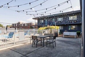 An outdoor seating area with a pool, a modern building with a balcony, and string lights. - Nashville Condo w/ Pool - 10 mins to Downtown (Nashville)
