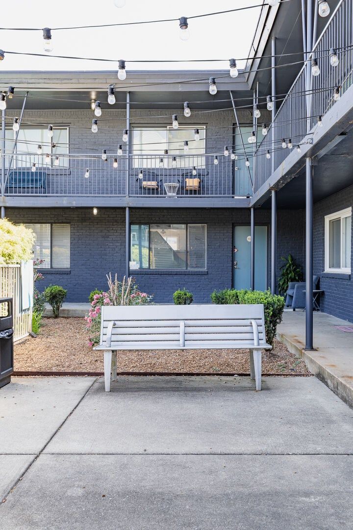 A two-story building with a balcony, outdoor seating, and a bench.