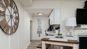 Een keuken met een grote houten klok, een tafel met een placemat en een muur waarop de letters 'EAT' staan.