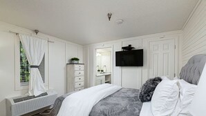 Een slaapkamer met een bed, een dressoir, een televisie en een airconditioning.