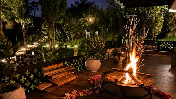 An outdoor patio with a fire feature, wooden benches, and a decorative flower arrangement.