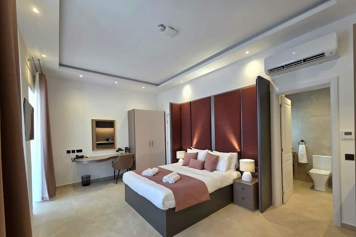 Una habitación de hotel moderna con una cama grande, mesitas de noche, un escritorio y un baño.