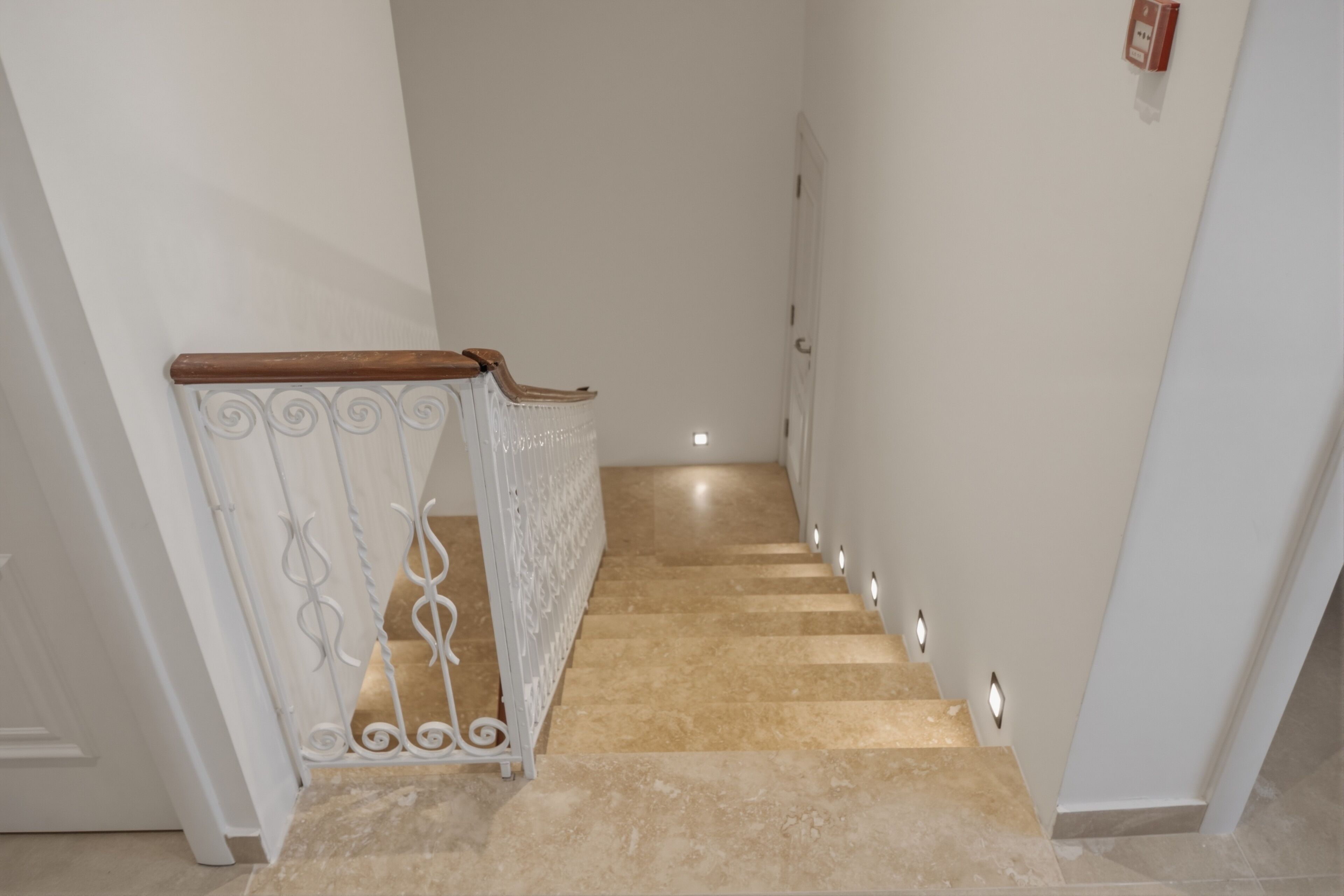 Una escalera con barandilla de madera y balaustres blancos que lleva a una puerta.