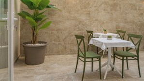 Uma área de refeições com uma mesa, cadeiras, um vaso de planta e um candeeiro fixado na parede.