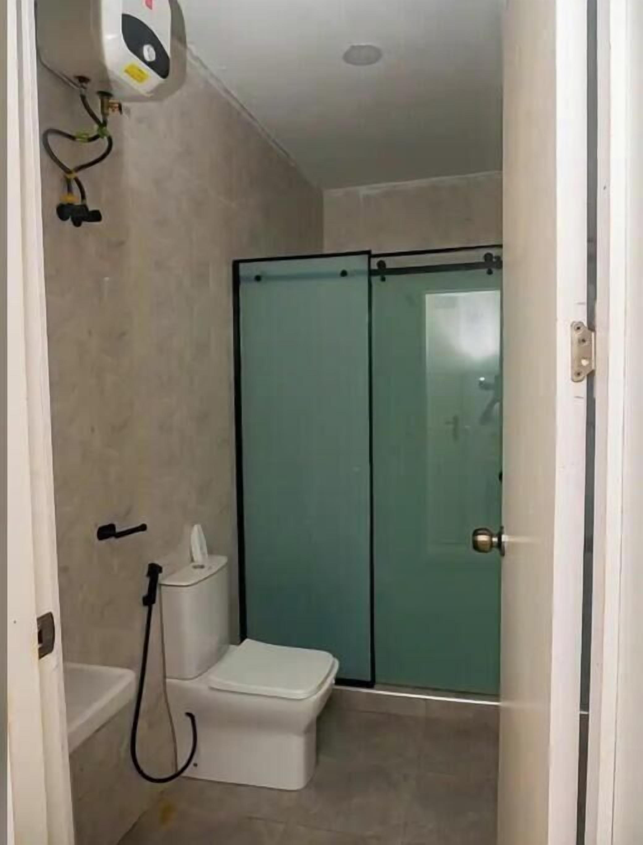 Une salle de bain comprenant des toilettes, un espace douche et une porte en verre.
