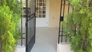 Una entrada protegida por un portón con puerta, rodeada de follaje.