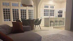 Una sala de estar moderna con un sofá, un comedor y una cocina visibles a través de un arco.