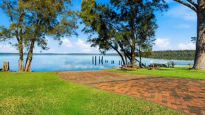 Un parque junto al lago con mesas de picnic y un sendero pavimentado.