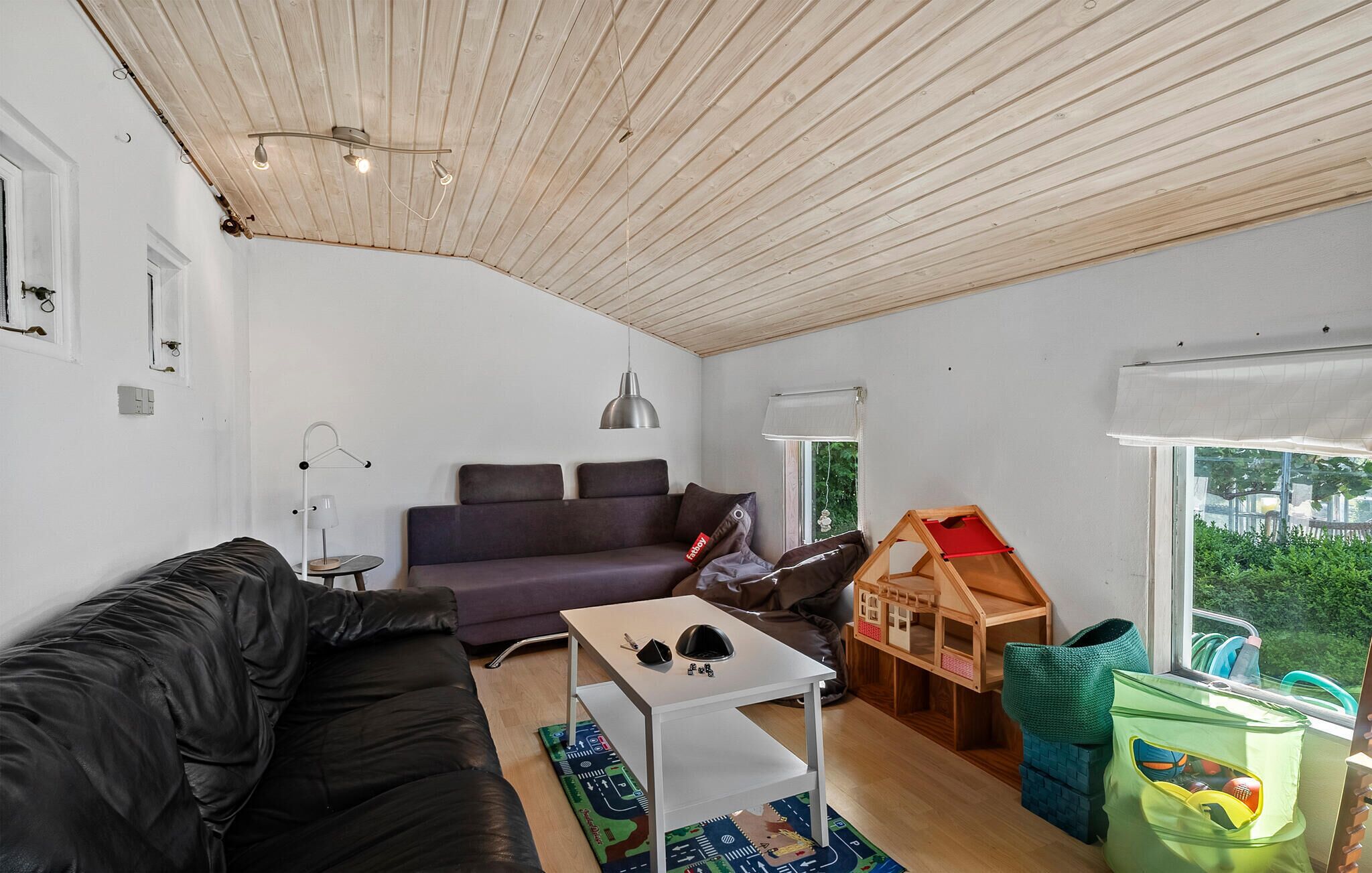 Een moderne woonkamer met een houten plafond, een bank, een bijzettafeltje en een poppenhuis.