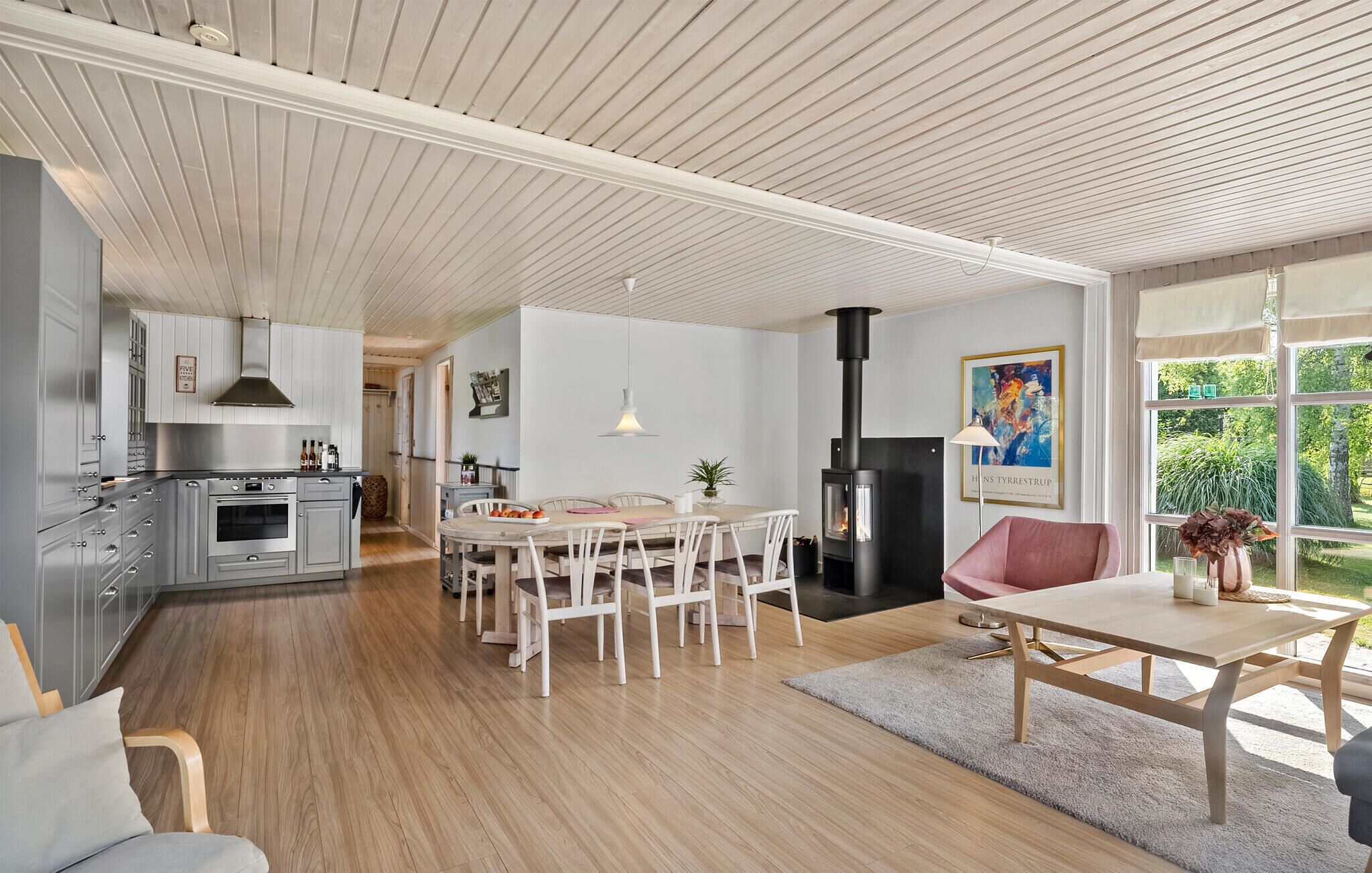 A modern kitchen with a dining area, wooden floors, and a large window.