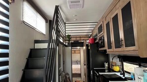 Une cuisine compacte équipée d’une cuisinière intégrée, d’un évier et de meubles de rangement en bois.