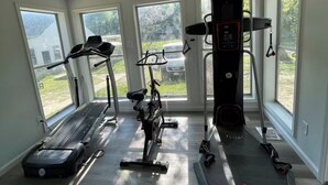 Une salle de sport à domicile équipée de tapis de course, d’un vélo elliptique et d’un appareil de marche en escalier.
