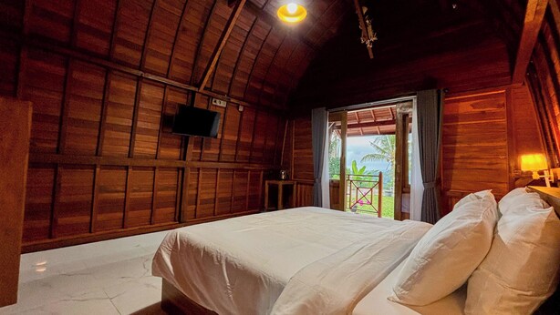 Quarto de madeira com uma cama, uma televisão e vista para o exterior.