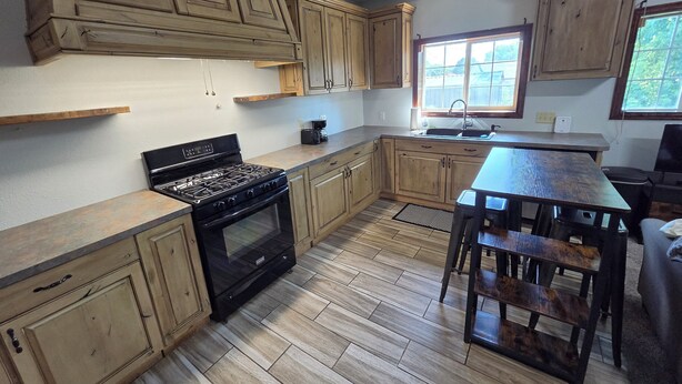 A kitchen with wooden cabinets, a black stove, and a window.