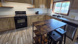 A kitchen with wooden cabinets, a stove, a sink, and a window.
