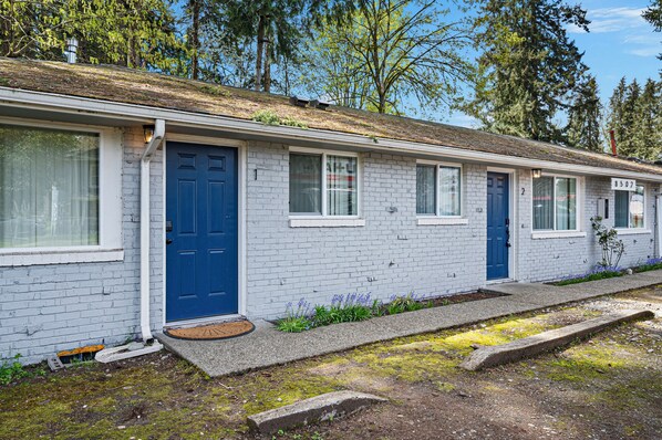 A single-story building with a blue door, white windows, and a brick exterior.