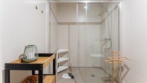 Ein modernes Badezimmer mit einer gläsernen Dusche, einem Holzboden und einem weißen Waschbecken.