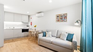 Eine moderne Wohnung mit Küchenzeile, Essbereich und Wohnzimmer mit Sofa und Tisch.