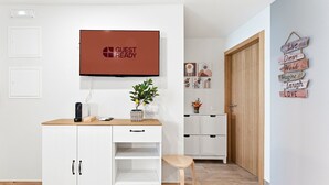 Ein Hotelzimmer mit einem weißen Schrank, einem Fernseher, einem kleinen Tisch mit Pflanze und einer Holztür.
