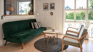 Ein gemütliches Wohnzimmer mit einem grünen Sofa, einem runden Tisch und zwei Stühlen.