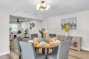A dining area with a round table set for six, chairs, a ceiling fan, and a wall-mounted painting. - Peaceful Getaway~ Heated Pool ~10 Min to Beach (Largo)