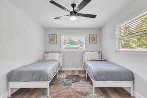A bedroom with two beds, a ceiling fan, a window with blinds, and a patterned rug. - Peaceful Getaway~ Heated Pool ~10 Min to Beach (Largo)